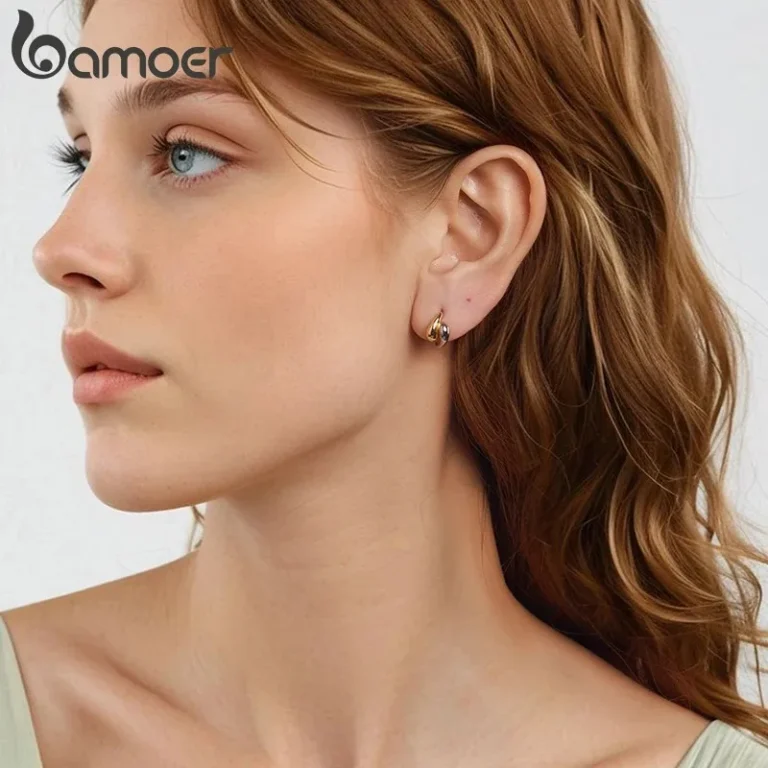 Nahaufnahme einer Frau mit zweifarbigen Tropfen-Creolen aus 925er Silber. Gold-Silber Ohrringe im Yin Yang Stil. Elegante Klappcreolen von Bamoer. Modische Silberohrringe als Geschenkidee. Zeitloser Schmuck für Damen.