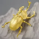 Goldener Käfer Schmuckverfahren: Einzigartige Brosche in Käferform, gefertigt aus glänzendem Gold. Detailreiche, strukturierte Oberfläche des Schmuckstücks.